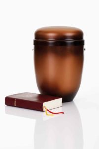 Imagem de biblia ao lado e urna para cremação