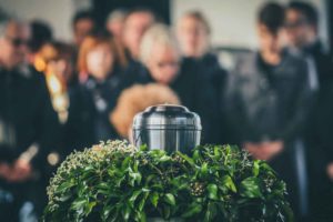 Imagem de urna envolta de folhas em funeral após família optar pela cremação