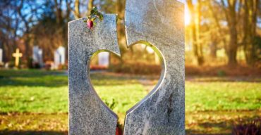 Cemitério jardim com uma pedra cortada em forma de coração em primeiro plano