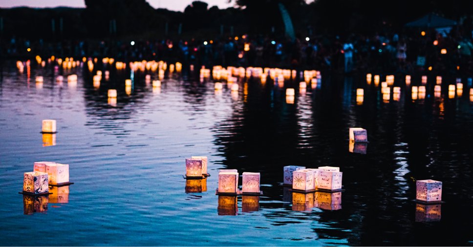 Lanternas iluminadas flutuando na água durante o Festival de Obon ao anoitecer.