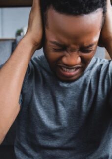 Jovem sentado no chão com expressão de dor e frustração, pautando a raiva no luto