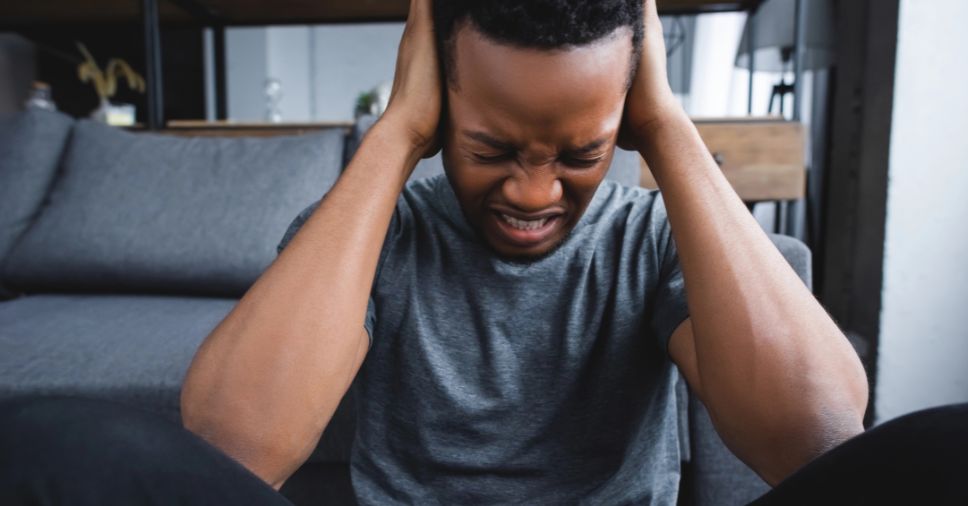 Jovem sentado no chão com expressão de dor e frustração, pautando a raiva no luto