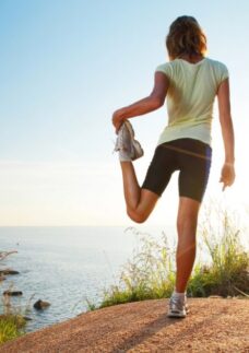 Jovem faz exercícios ao ar livre no topo de um morro mostra que o esporte pode ajudar no luto.