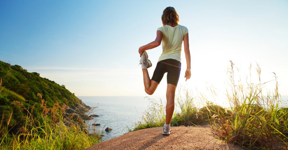 Jovem faz exercícios ao ar livre no topo de um morro mostra que o esporte pode ajudar no luto.