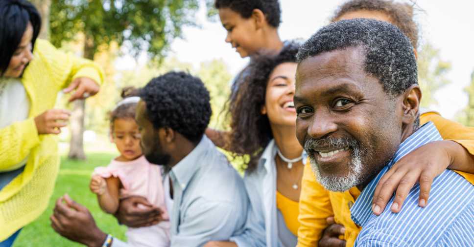 Homem negro sorri com a família no parque por estar preparado para morte.
